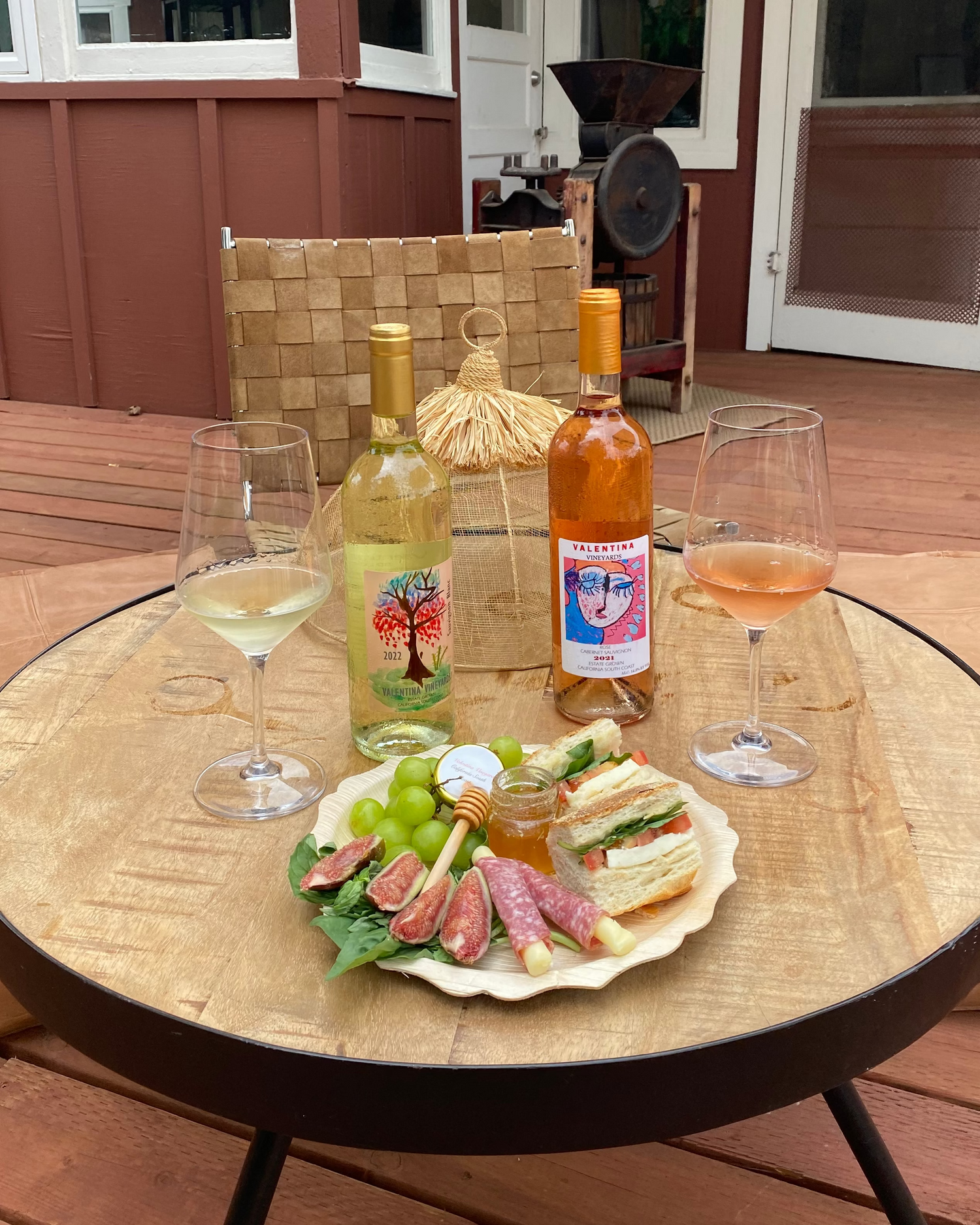 Outdoor setting with a round table featuring wine, snacks, and a salad.